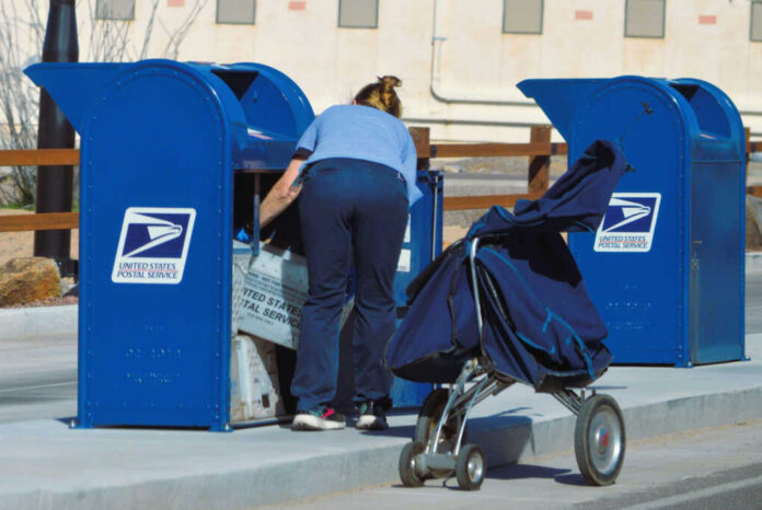 Postal worker loading mail into a blue USPS collection box