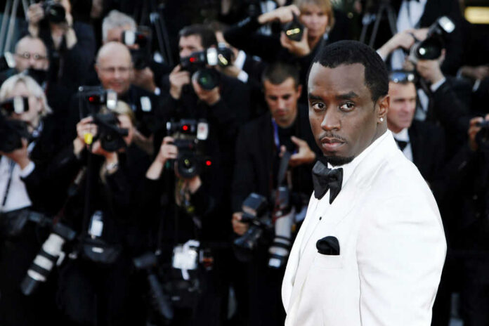 48621519 Man in white tuxedo surrounded by photographers.