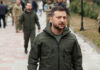 Zelensky walking outdoors with military personnel nearby.