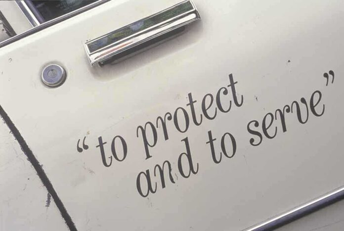 shutterstock_106869842 Close-up of a police car door with the phrase to protect and to serve