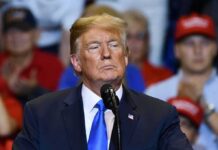 Chilling Iran Broadcast Taunts Trump man in suit speaking at a rally podium
