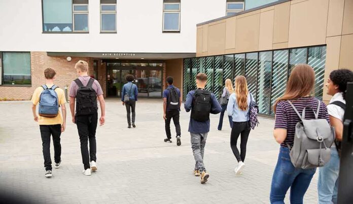 Students with backpacks walking toward a school entrance