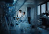 Two scientists working in a laboratory with a microscope and computer screens