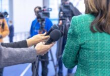 Press Battle Erupts: China Warns Retaliation Hands holding microphones in front of a person at a press conference