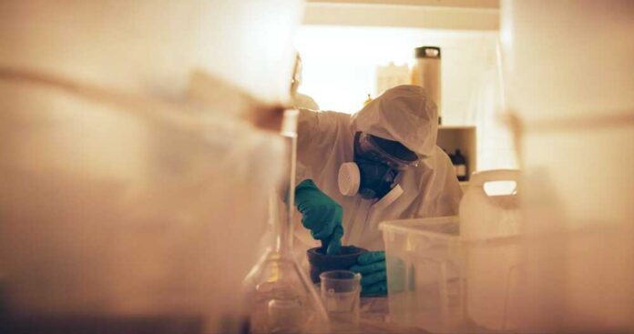 Drugs,,Person,And,Gas,Mask,In,Lab,For,Production,Of Scientist in protective gear mixing substance in a lab