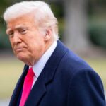 Library Dedication Sparks MAGA Frenzy A political figure with a serious expression, wearing a dark coat and a bright tie, outdoors