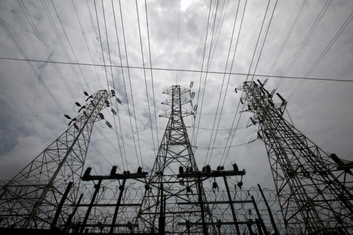 High-voltage,Power,Lines,Stretch,Across,The,Sky,Outside,A,Tata High-voltage transmission towers and power lines against a cloudy sky