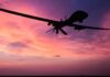 Cheap Missiles? NZ Bets On One-Way Drones drone silhouette flying against a pink and purple sunset sky