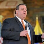 Monumental Defeat—or Manufactured Drama? A man in a suit speaking into a microphone at an event