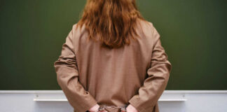 Person in handcuffs facing a chalkboard