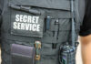 Stunning Intel Snub Exposed — Trump Left Open Tactical vest with equipment and a visible service patch