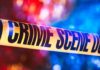 Crime scene tape with blurred emergency lights in background
