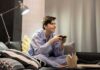 Teen in pajamas playing video games on a couch