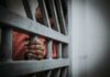 Victims Blindsided by Quiet Parole Shift Hand gripping jail bars