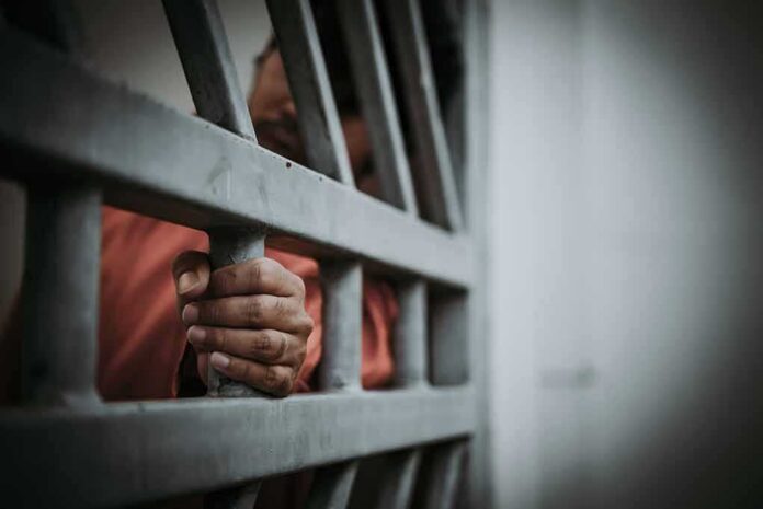 Hand gripping jail bars