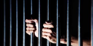 hands gripping prison bars