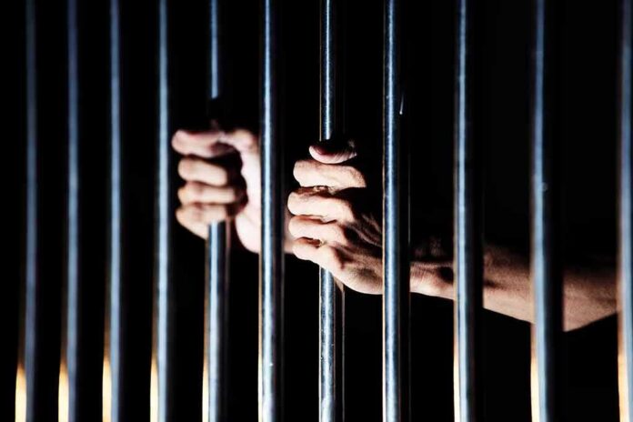 hands gripping prison bars