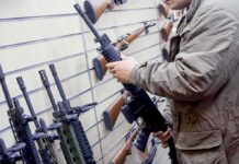Person examining a black rifle in a gun store