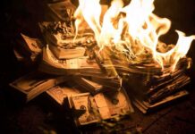 Stacks of U.S. dollar bills burning in bright flames