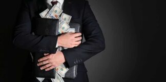 Businessman hugging briefcase stuffed with cash