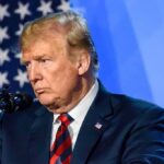 Political Payback Or Risk Move? Trump Banked Out man at podium speaking into microphone