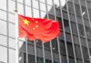 Beijing’s Market Reversal Slams U.S. Industry Chinese flag waving against glass office building