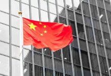Beijing’s Market Reversal Slams U.S. Industry Chinese flag waving against glass office building