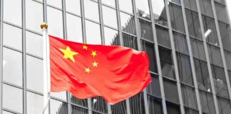 Chinese flag waving against glass office building