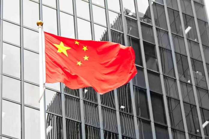 shutterstock_141608113 Chinese flag waving against glass office building