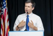 man in white shirt and blue tie speaking at a podium