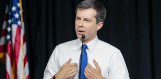 man in white shirt and blue tie speaking at a podium