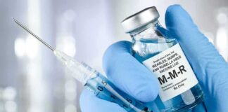 Gloved hands holding a vaccine vial and syringe