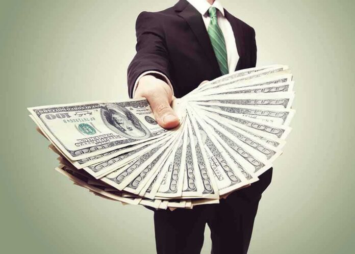 shutterstock_146762978 Businessperson holding a fan of US dollar bills