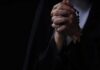 Hands clasped in prayer holding a rosary