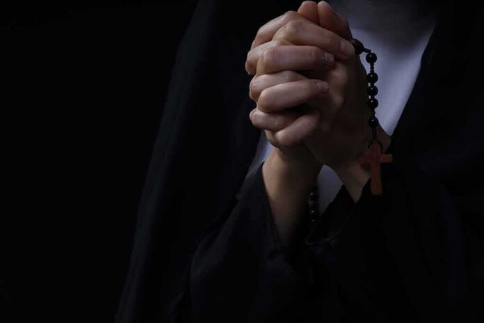 Hands clasped in prayer holding a rosary