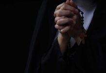 Hands clasped in prayer holding a rosary