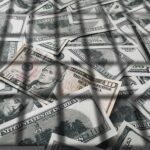 DOJ Blitz Nails 455 In Health Scams pile of us dollar bills with a ten-dollar note on top