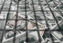 DOJ Blitz Nails 455 In Health Scams pile of us dollar bills with a ten-dollar note on top