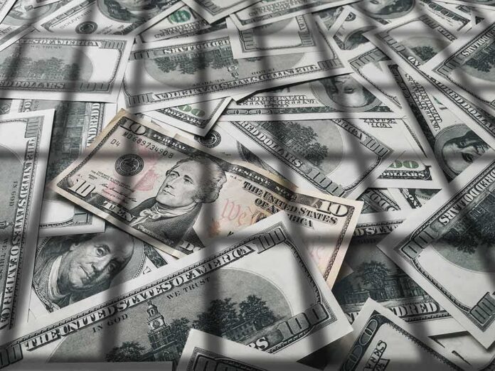 pile of us dollar bills with a ten-dollar note on top