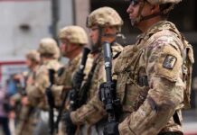 Guard Major Admits Fraud—Where’d $54K Go? Soldiers in camouflage gear stand in formation holding rifles
