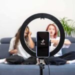 smartphone on ring light filming two people on a couch