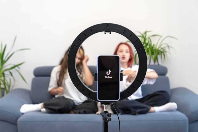 shutterstock_2170134629 smartphone on ring light filming two people on a couch