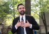 Court Freeze Exposes Botched Tax Rollout Man in suit speaking with hands on chest outdoors