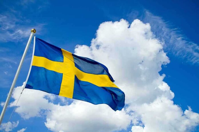 shutterstock_627344084 Sweden flag waving against a blue sky with clouds