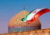 Iranian flag waves before an ornate mosque dome at sunset