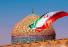 Mass Mobilization – What’s Iran Prepping For? Iranian flag waves before an ornate mosque dome at sunset