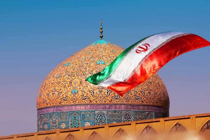 shutterstock_1140569927 Iranian flag waves before an ornate mosque dome at sunset
