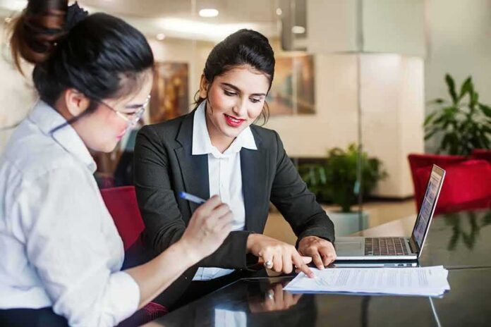 shutterstock_1163401579 Two businesswomen reviewing documents at a desk