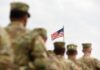 U.S. Warplanes Hit Cartels – War Moves Offshore U.S. flag flying above a formation of soldiers in uniform