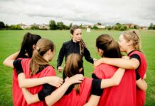 Voters Revolt: Dems Flip On Women’s Sports Coach talks to youth team in a huddle on a field